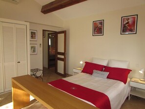 A bedroom with a bed, bedside tables, a bench, a wardrobe, and a door to a bathroom. - Barjac Villa Pastis - Self-catering cottage with swimming pool and view of the Cevennes mountains (Barjac)