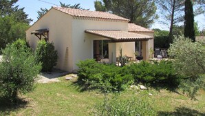 A single-story house with a tiled roof, surrounded by greenery and trees. - Barjac Villa Pastis - Self-catering cottage with swimming pool and view of the Cevennes mountains (Barjac)