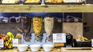 Een ontbijtbuffet met diverse granen, fruit en brood.