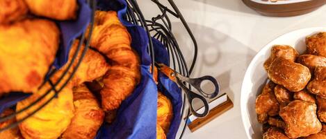 A basket of croissants and a bowl of cookies on a table.