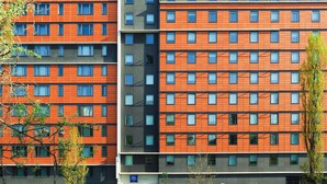 Een modern hotelgebouw met een ruitpatroon van ramen en een oranje gevel.
