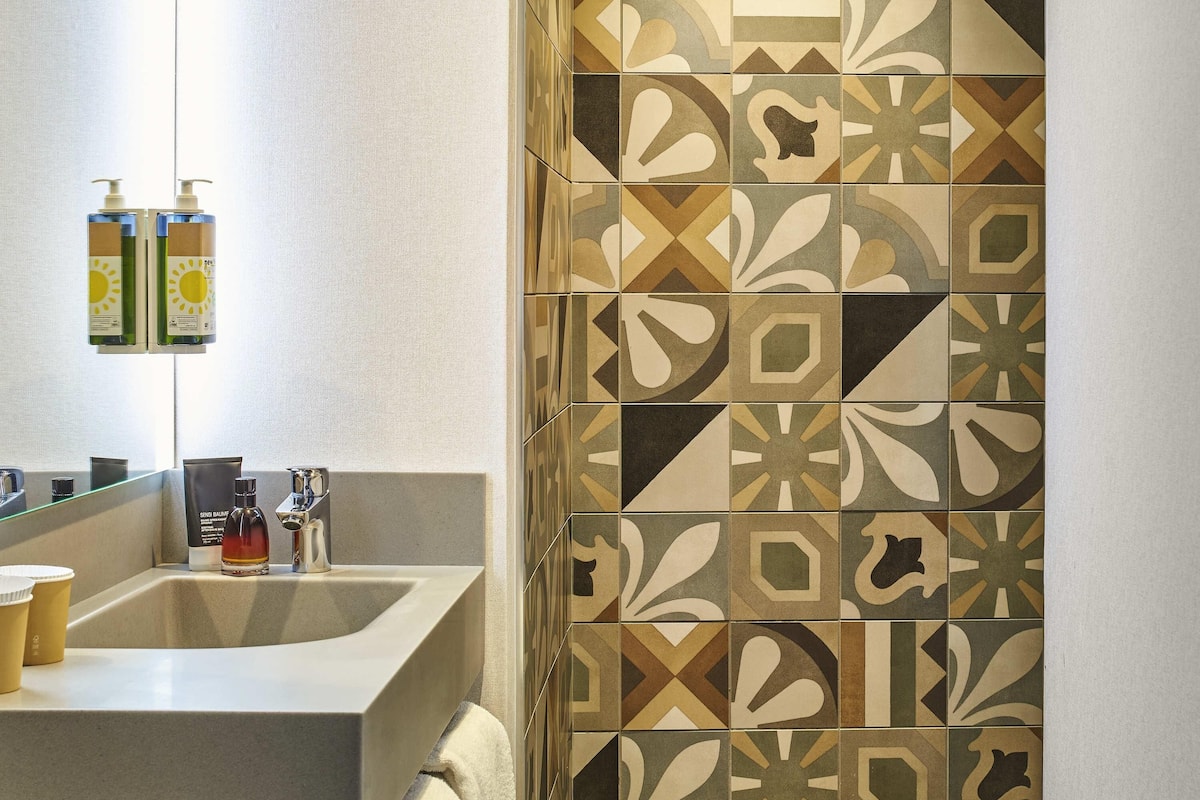 Ein Badezimmer mit Waschbecken, Spiegel und Fliesen mit Muster.