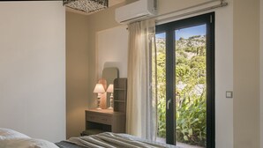 Ein Schlafzimmer mit einem Bett, einem Nachttisch mit Lampen, einem Schminktisch und einer Glastür, die in einen Garten führt.