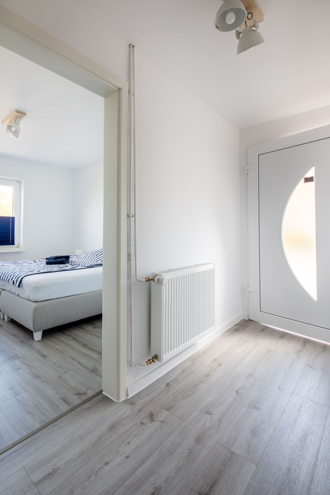 A modern bedroom with a bed, a radiator, and a large window.