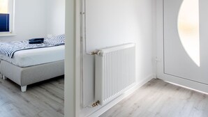 A modern bedroom with a bed, a radiator, and a large window. - Vacation apartment Ankerplatz in House Annika in Schillig-Horumersiel (Wangerland)