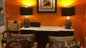 Quarto com duas cadeiras, uma mesa e duas luminárias.