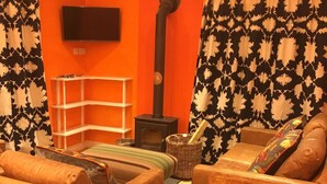 Uma sala de estar acolhedora com lareira, televisão na parede e cortina estampada.