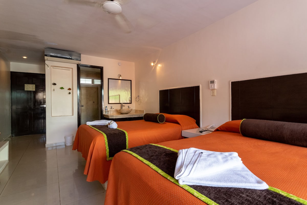 A hotel room with two beds, a bathroom, and a small sitting area.