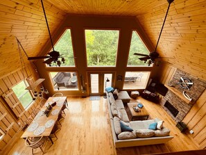 A spacious cabin with a high ceiling, wooden walls, and large windows offering a view of the outdoors.