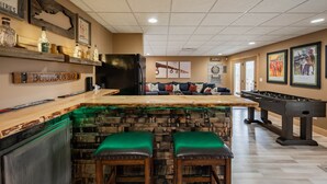 Un área de bar con taburetes, una mesa de fútbol de mesa y un dardo.