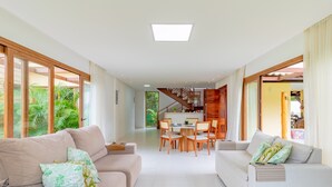 Ein geräumiger Wohnbereich mit zwei Sofas, einem Esstisch und einer Treppe, die zu einer oberen Ebene führt.