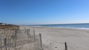 Une plage avec une clôture en bois et des maisons en arrière-plan.