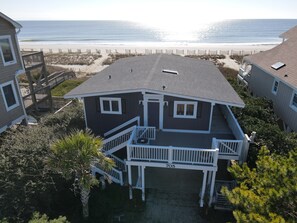 Une maison à deux étages avec un balcon, le numéro « 705 » sur la façade, et une vue sur la plage en arrière-plan.
