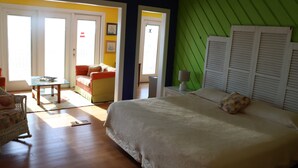Une chambre à coucher comprenant un lit, une chaise, une table et une porte donnant sur une autre pièce.