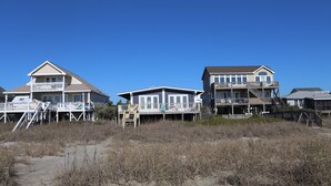 Une propriété située en bord de mer, comprenant plusieurs maisons dotées de balcons, de terrasses en bois et d’escaliers menant à la plage.