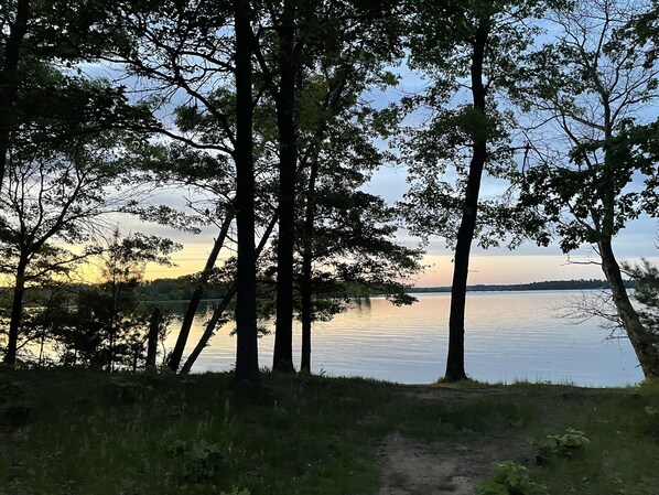 A natural landscape with a body of water, trees, and a path leading to the water.
