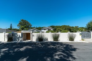 A gated residential area with modern houses, a clear blue sky, and a well-maintained lawn.