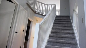 Eine Treppe mit weißen Geländern und Teppichstufen, die zu einer oberen Etage führt.