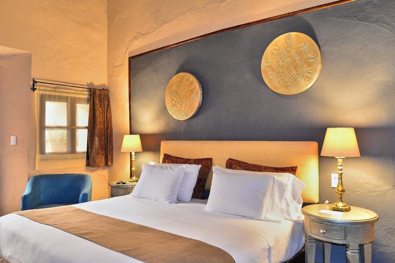 A hotel room with a large bed, two bedside lamps, a chair, and a window with curtains.