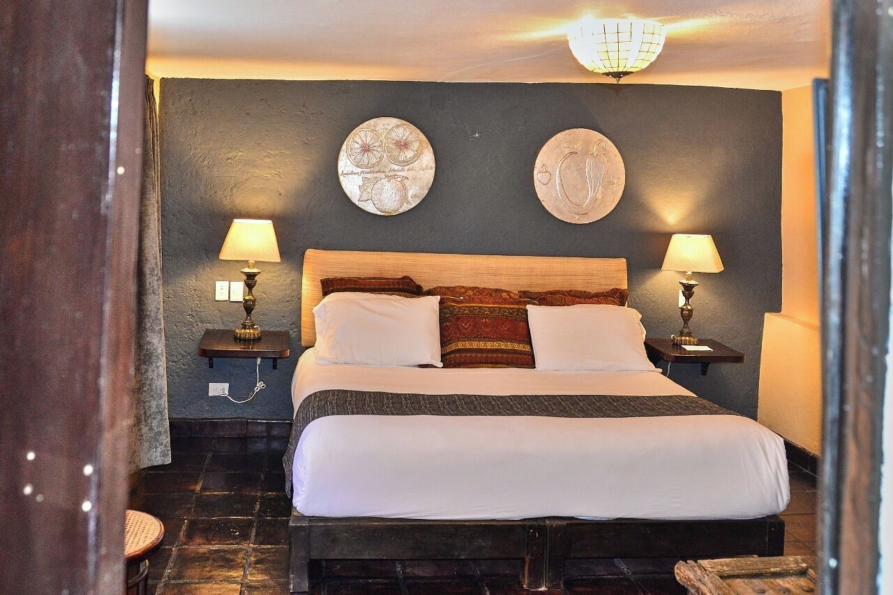Un letto con lenzuola bianche, due comodini con lampade e due decorazioni a parete.