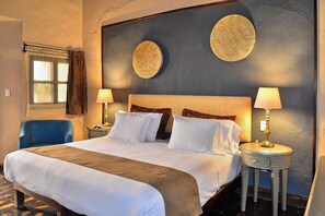 Una habitación de hotel con una cama grande, dos mesitas de noche, una silla y decoración en la pared.