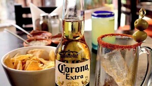 A bottle of Corona Extra beer, a bowl of nachos, and a margarita with an olive garnish on a table. - Hotel Mesones 49 (San Miguel de Allende)