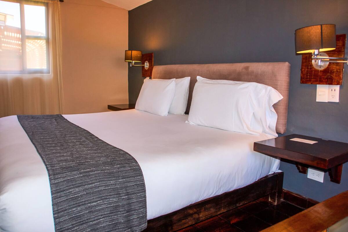 A hotel room with a large bed, two bedside tables, and a nightstand.
