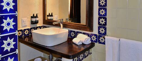 Un baño con un lavabo blanco, un espejo y baldosas azules y blancas con diseño.