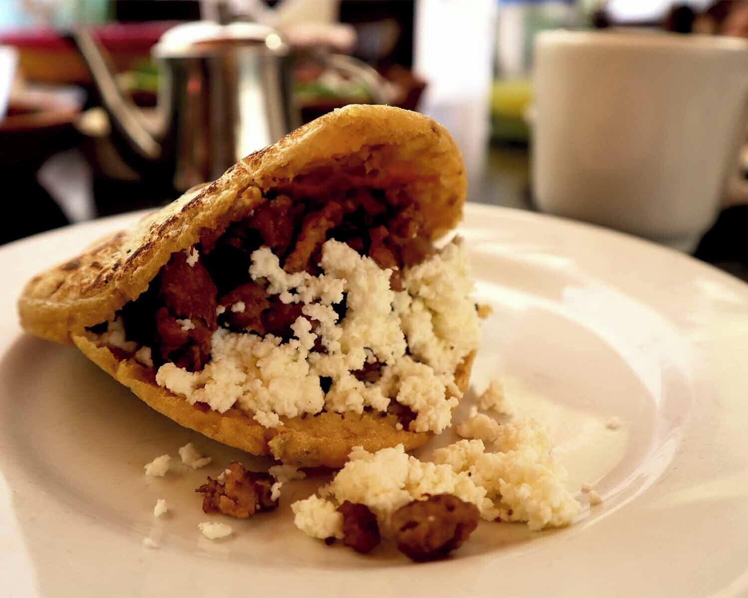 A pastry with a flaky crust, a filling that appears to be red fruit, and crumbled white cheese on a plate.