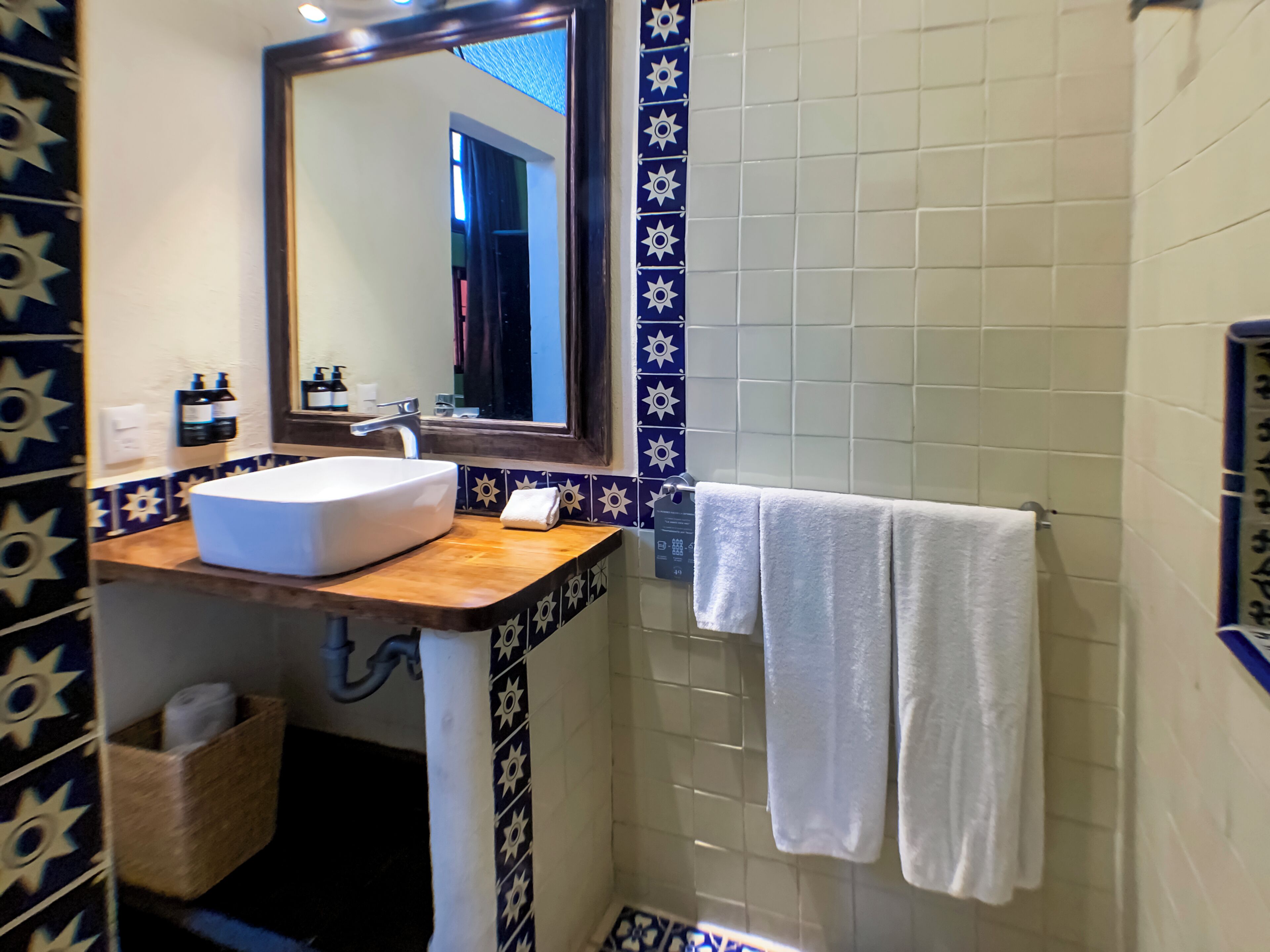 Un baño con un lavamanos blanco, un espejo y un perchero para toallas.