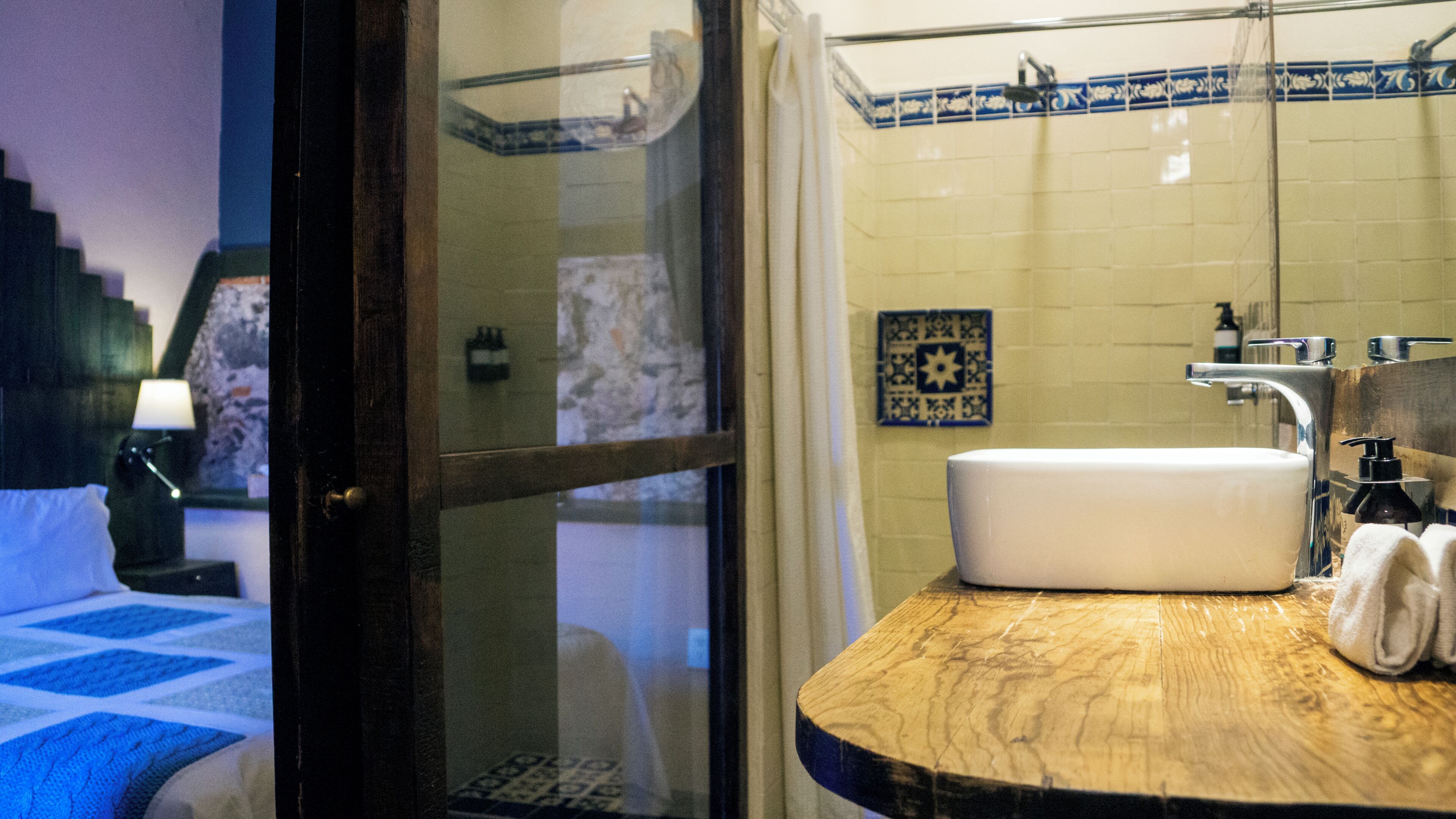 Une salle de bain avec un meuble-lavabo en bois, un lavabo blanc et un espace douche.