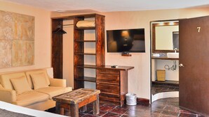 A living room with a sofa, a wooden cabinet, a television, and a door marked with the number 7. - Hotel Mesones 49 (San Miguel de Allende)