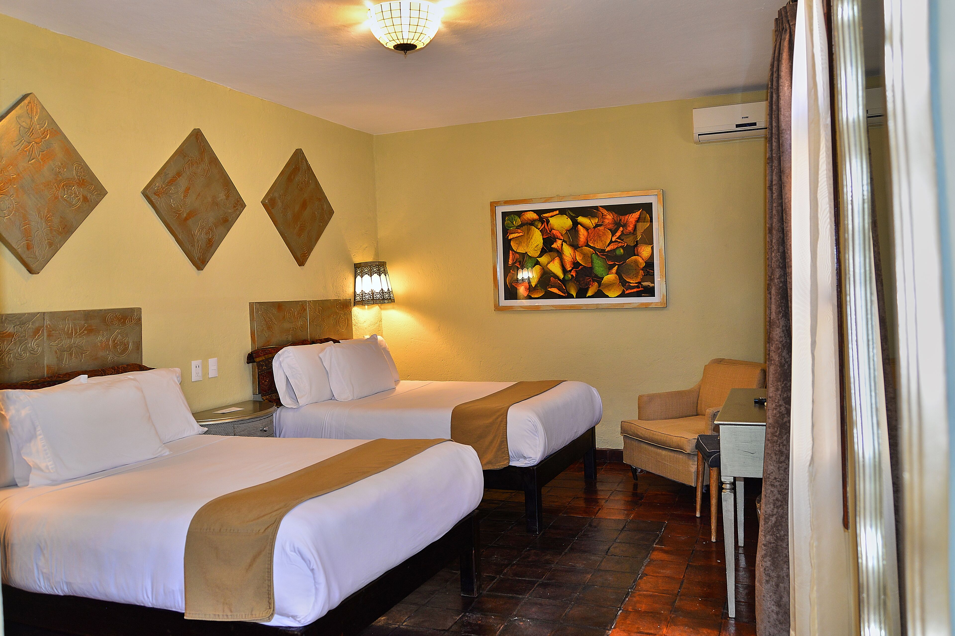 Habitación de hotel con dos camas, un sofá, una mesa y un cuadro en la pared.