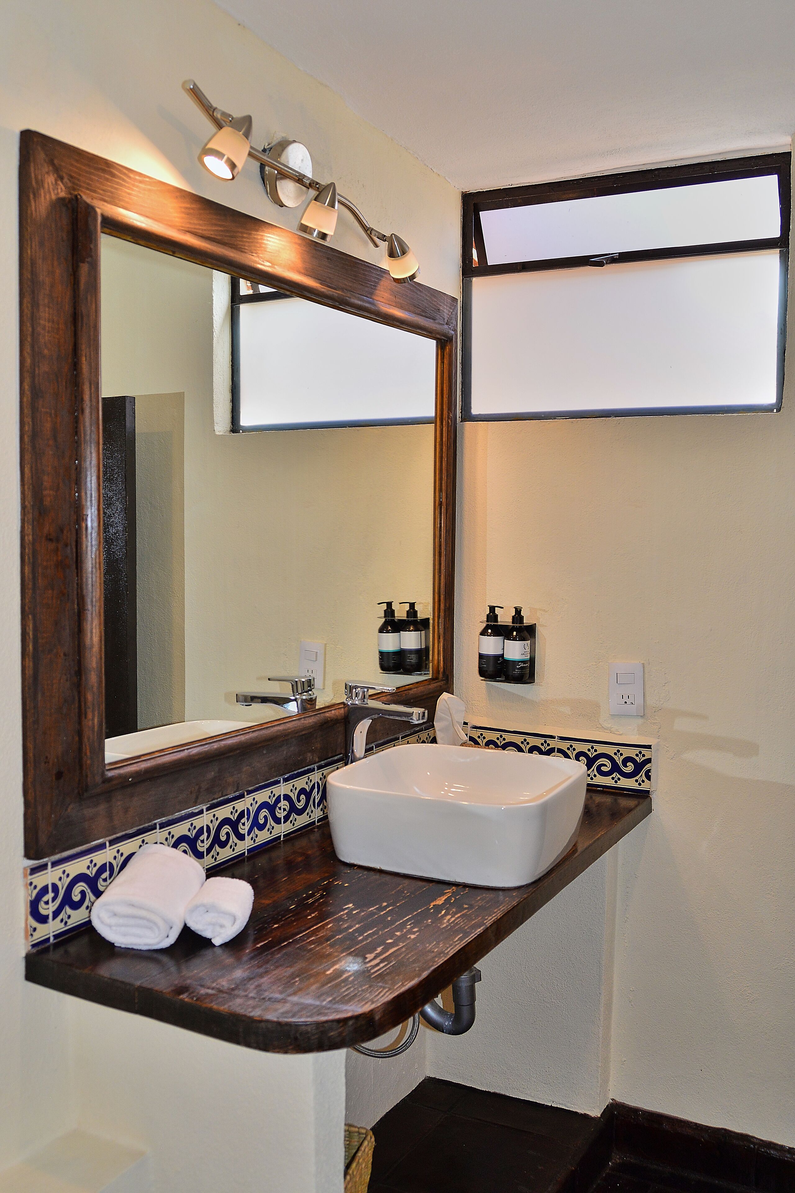 A bathroom with a large mirror, a white sink, and a towel rack.