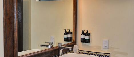 A bathroom with a large mirror, a white sink, and a towel rack.