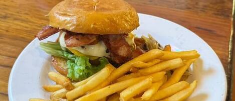 Un plato con una hamburguesa y papas fritas sobre una mesa de madera.