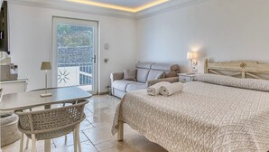 Een slaapkamer met een bed, bureau, stoel, bank en een raam met jaloezieën.