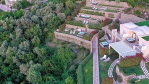 Luchtbeeld van een moderne villa met meerdere terrassen, zitplaatsen buiten en een pad van natuursteen.