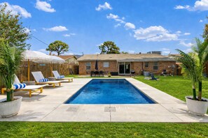 A backyard with a swimming pool, lounge chairs, and a barbecue area. - Walk to World Cup! - Gated Heated Pool - Playset - 6 Beds (Arlington)