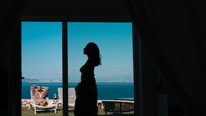 A room with a large sliding glass door leading to a balcony with a view of the sea and distant cityscape. - Villa DAlessandro Rosaria, private apartment and private hot jacuzzi (Anacapri)