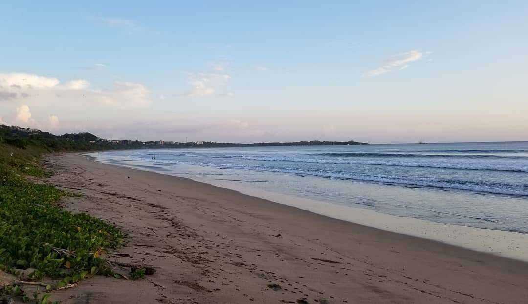A beach with a sandy shore and gentle waves.