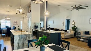 A modern kitchen with a marble island, dining area with a table and chairs, and a living room with a sofa and coffee table. - LARGE MODERN 4 BEDROOM HOME. VERY PRIVATE w HOT TUB & 3 acres!  (Crystal River)