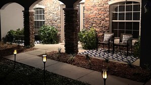 A stone exterior with arched windows and a patio area with outdoor seating. - LARGE MODERN 4 BEDROOM HOME. VERY PRIVATE w HOT TUB & 3 acres!  (Crystal River)