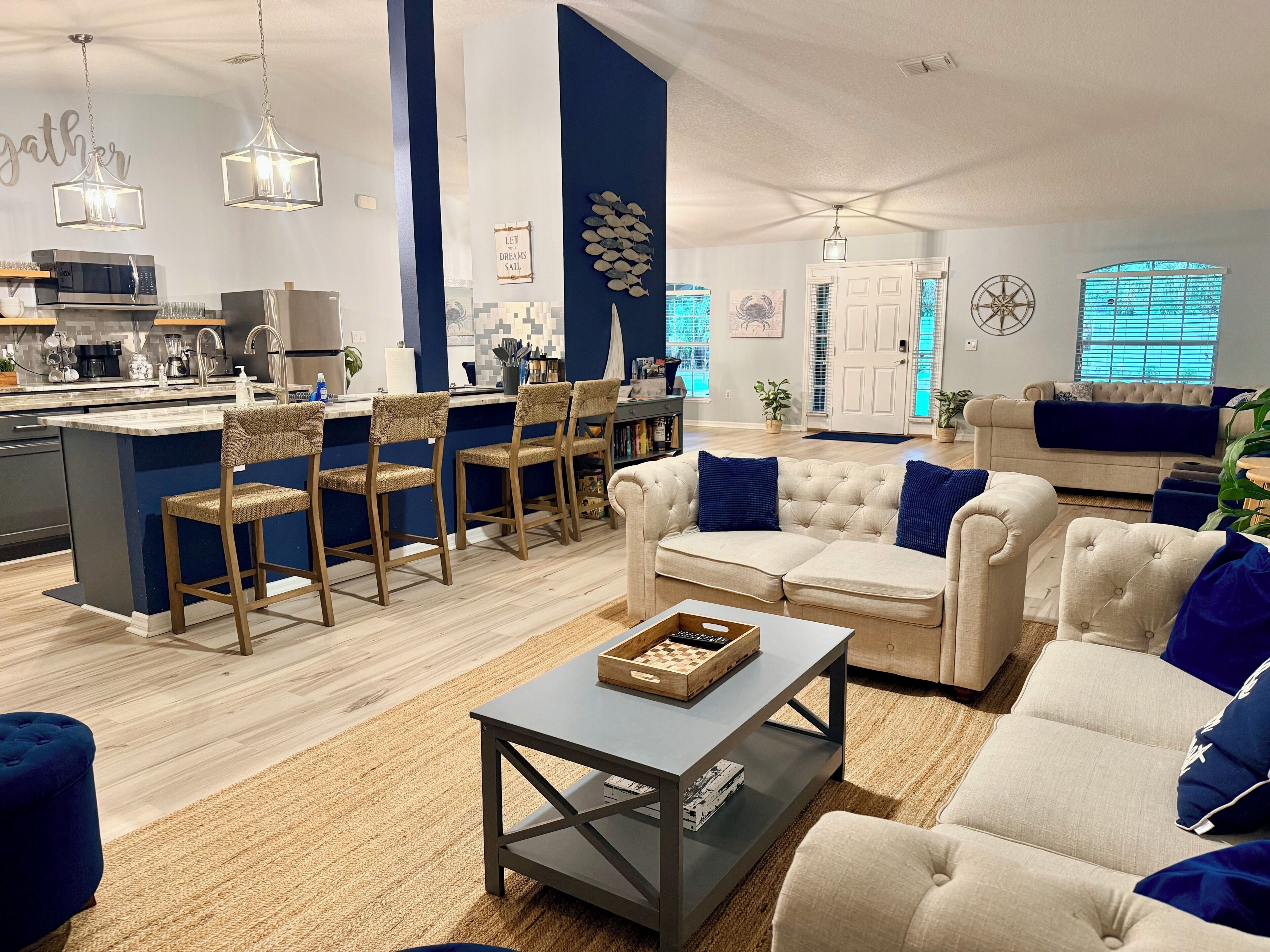 Un salon moderne avec un canapé, une table basse et des fauteuils. Il y a également un coin cuisine équipé d’un four à micro-ondes et d’un évier.