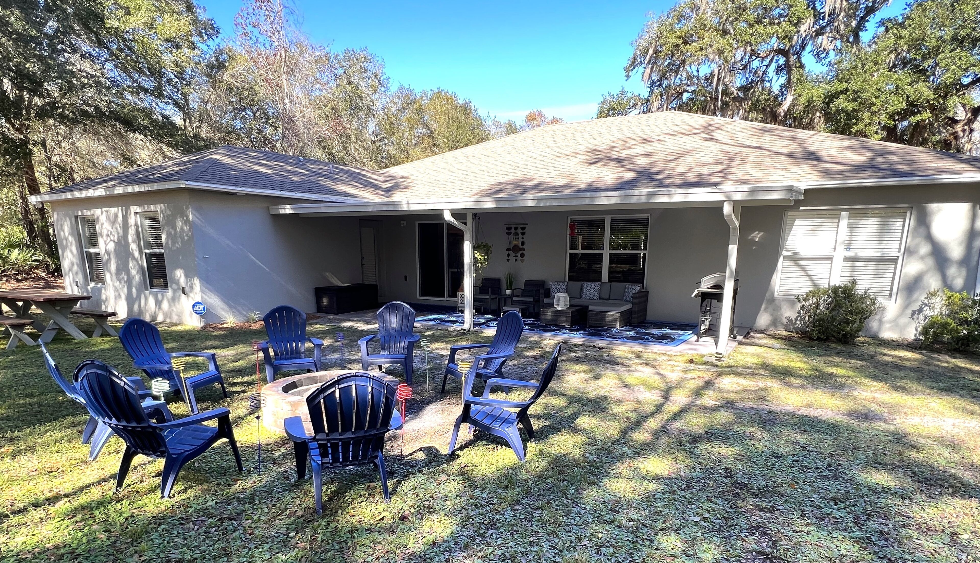 A house with a covered patio, outdoor seating, and a barbecue grill.