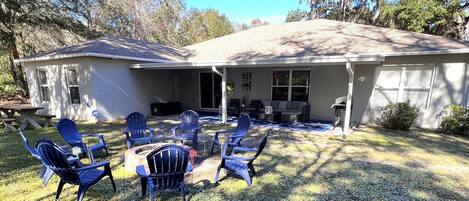 A house with a covered patio, outdoor seating, and a barbecue grill.