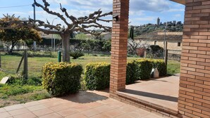 A patio area with a brick wall, a metal fence, and a view of a hilly landscape with buildings. - House in a quiet area with views of the old town of Pals (Pals)