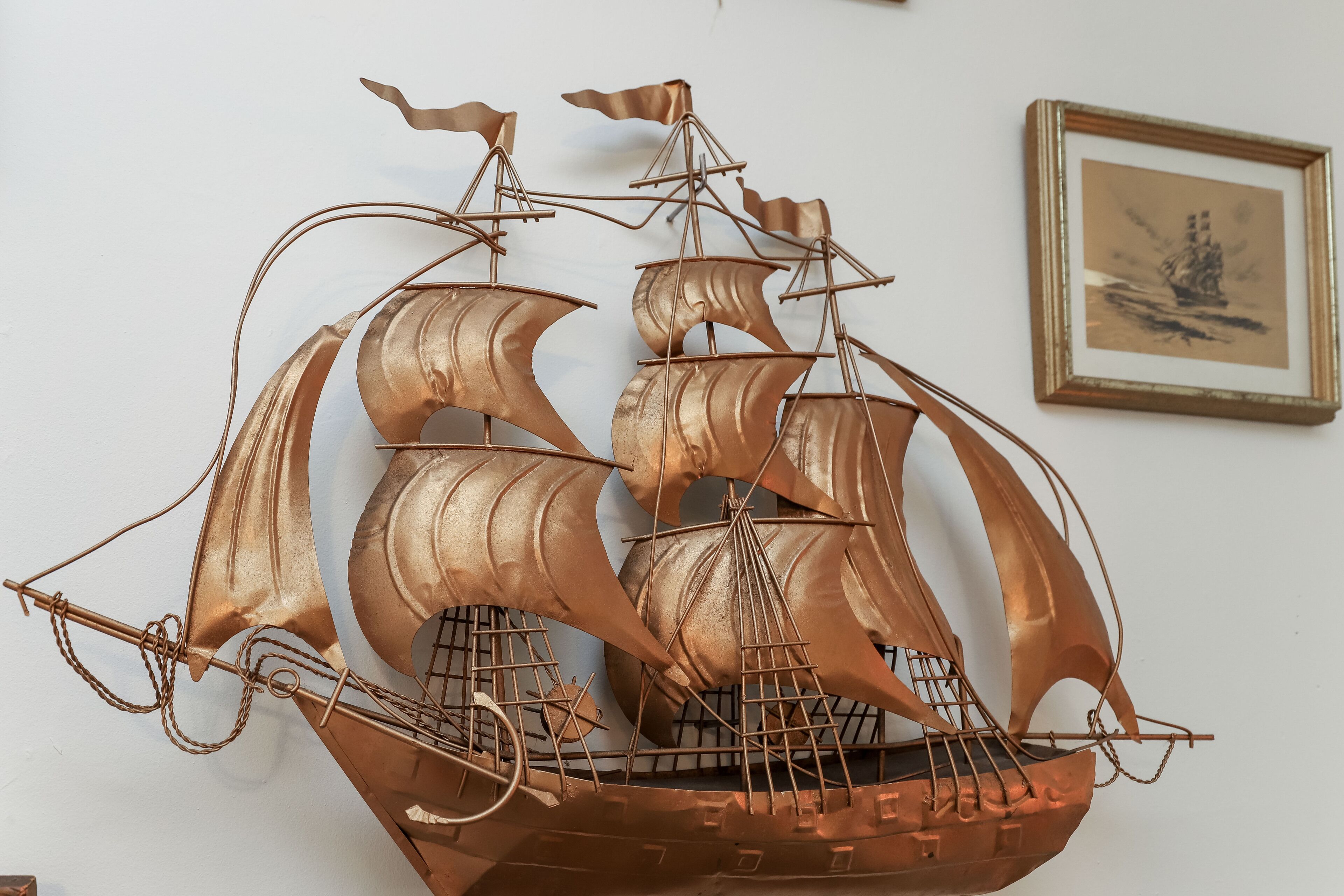Una escultura de barco en color cobre montada en una pared.