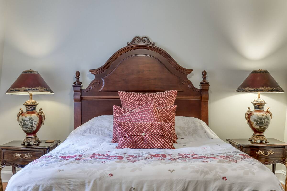 A neatly made bed with a floral bedspread, a wooden headboard, and two bedside tables with ornate lamps.