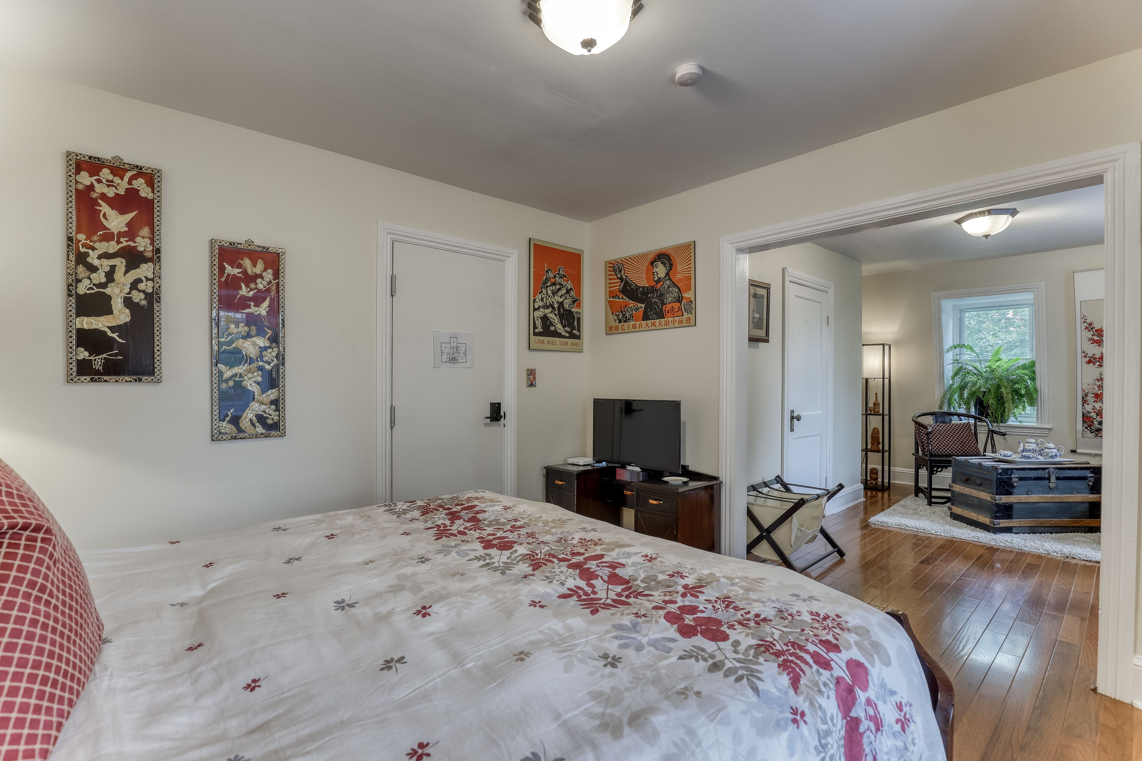 A bedroom with a bed, a desk, a chair, and artwork on the walls.